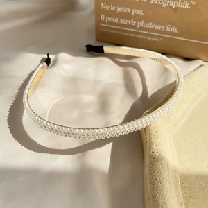 Detailopname van de drielaagse parelhoofdband met gouden basis op zachte zijde