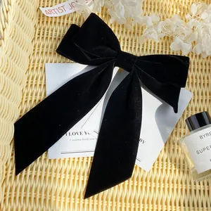 Elegant black velvet bow hair clip with double long tails on a rustic lifestyle backdrop
