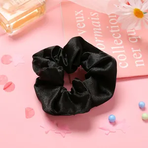 Détail d'un chouchou en satin noir élégant avec des plis soyeux sur fond rose décoratif
