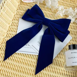 Close-up of a dark blue velvet bow hair clip with ribbons in a rustic woven basket