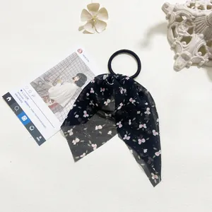 Detailed macro view of black floral chiffon hair scrunchie with long ribbon streamers
