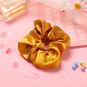 Détail d'un chouchou en satin doré soyeux avec des plis doux et une texture brillante