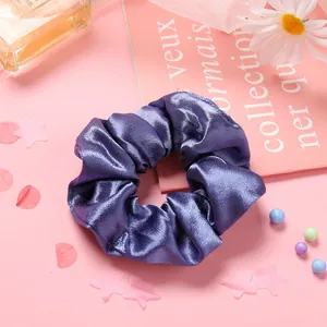 Gros plan sur un chouchou en satin violet foncé montrant texture lisse et reflets