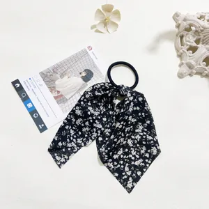 Close-up of a dark blue floral bow hair tie with white patterns and elastic band