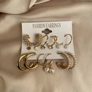 Detailed set of six pairs of gold earrings with pearls on silk background