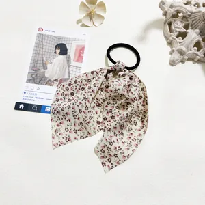 Floral bow hair tie with red-brown flower patterns on a white cream fabric base