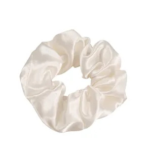 Chouchou en satin crème lustré avec élastique sur fond blanc impeccable
