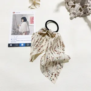 Detail of floral bow hair scrunchie with beige fabric and brown flower patterns