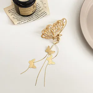 Détail de la pince à cheveux papillon dorée avec chaînes à pompons élégantes et breloques