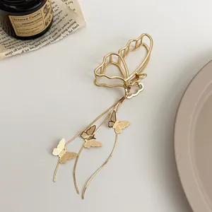 Détail de la pince à cheveux papillon dorée avec élégant gland en métal et pendentifs