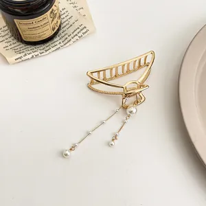 Détail d'une pince à cheveux dorée avec pampilles et perles blanches élégantes