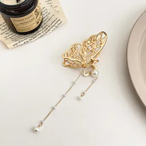 Détail de la pince à cheveux papillon dorée avec d'élégantes chaînes à perles