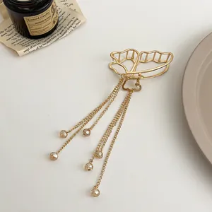 Détail d'une pince à cheveux papillon dorée avec chaînes à glands et perles ambrées