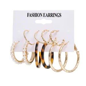 Set de pendientes dorados con perlas, aros de carey y diseños de metal entrelazado