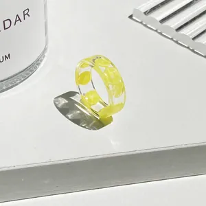 Anello in resina trasparente con fetta di limone su uno sfondo bianco professionale
