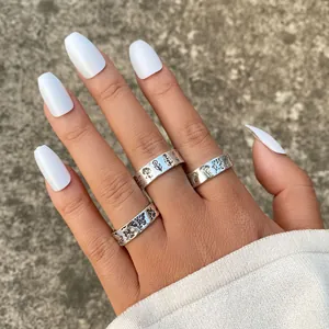 Detailed macro view of silver rings featuring embossed floral and butterfly patterns