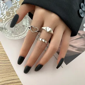 Close-up of three vintage silver heart rings worn on a hand with black matte nails