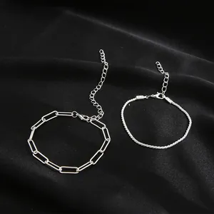 Dettaglio di bracciali argentati a strati con maglie a graffetta e catena a trama