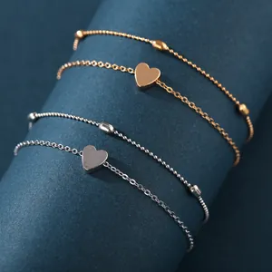 Minimalist four-piece set of gold and silver anklets with heart charms and beads