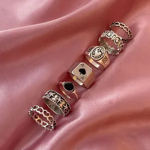 Gothic punk silver ring set with spade A and heart patterns on pink silk background