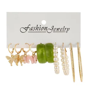 Detail of 6-pair earring set featuring gold butterflies, green resin and pearl hoops