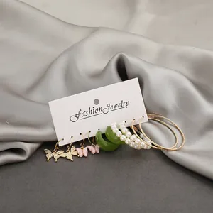 Close-up of 6-pair gold butterfly and pearl earring set on a display card