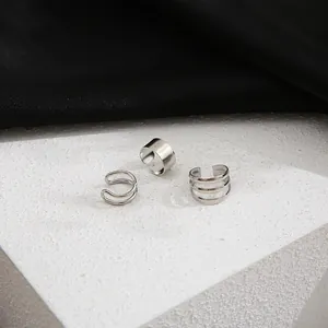 Detailed close-up of three silver non-pierced ear cuffs on a minimalist pedestal