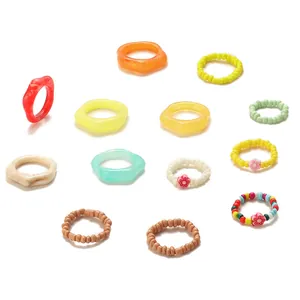 Dettaglio del set da 13 pezzi con anelli in resina colorata e gioielli con perline
