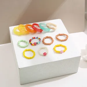 Dettaglio di anelli colorati in resina e perline fatti a mano con fiori su supporti bianchi