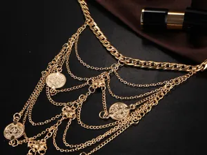 Détail macro d'une chaîne de corps vintage dorée avec pièces sur tissu en soie noire