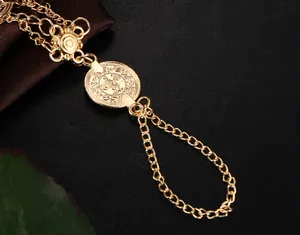Détail macro d'une chevillère dorée vintage avec pendentif pièce et chaîne florale
