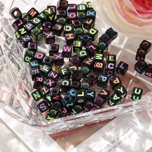 Vue macro de perles alphabet carrées noires avec lettres colorées dans un bol en verre
