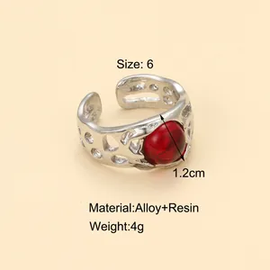 Détail de bague vintage argentée avec pierre en résine rouge et texture ajourée