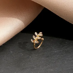 Eleganter Blatt-Ohrclip aus Gold mit glitzernden Kristallen auf grauem Stein
