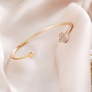 Detail van vergulde open hart armband met kristallen op zachte roze zijden stof