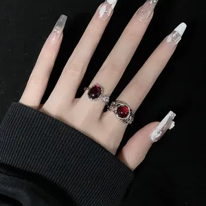 Détail macro de bagues gothiques en argent avec pierres rouges et texture ajourée sur modèle