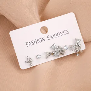 Détails de boucles d'oreilles étoile et nœud argentées avec zircon sur carte de support