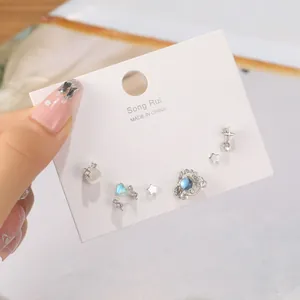 Vue détaillée d'un ensemble de boucles d'oreilles cœur et étoile avec pierres bleues