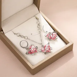 Détail du collier et des boucles d'oreilles cœur rose dans un coffret à bijoux