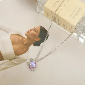 Detail of pink crystal heart planet necklace on a magazine with a perfume bottle