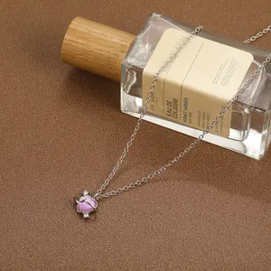 Detailed view of silver necklace featuring a sparkling pink heart planet pendant and small gems