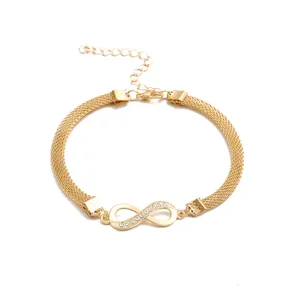 Detalle del dije infinito con diamantes incrustados en tobillera de malla dorada