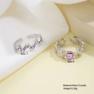 Silver alloy open rings set with purple heart crystals and stars on elegant silk cloth
