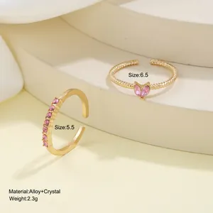 Gold open heart ring set with pink crystals and twisted band on white pedestals