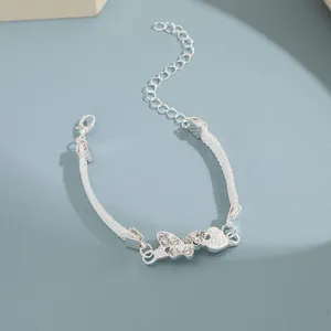 Detalle de la pulsera de mariposa plateada con diamantes de imitación y colgante de corazón