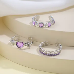 Close-up of three silver adjustable rings with purple zircon stones on a beige stand