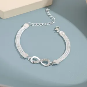 Detalle de tobillera de infinito plateada con cristales y cadenas de metal trenzadas