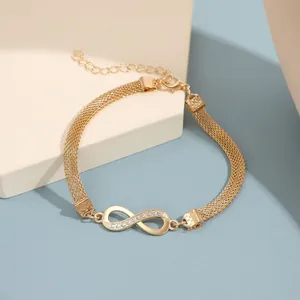 Detalle de tobillera con símbolo de infinito y cristales en cadena de malla dorada