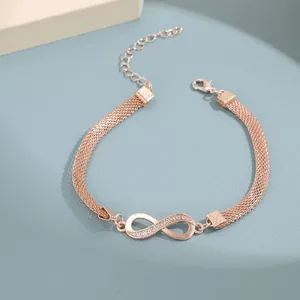 Detalle macro de tobillera de infinito en oro rosa con pedrería y cadena de malla