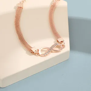 Detalle de una tobillera de infinito en oro rosa con cristales brillantes y banda de malla